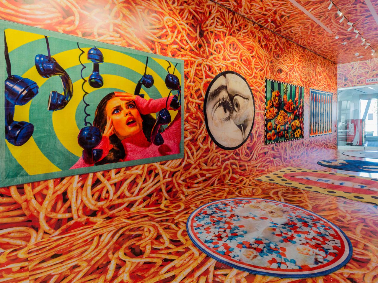 Hallway wrapped in detail image of spaghetti, psychedelic photos hanging on wall.