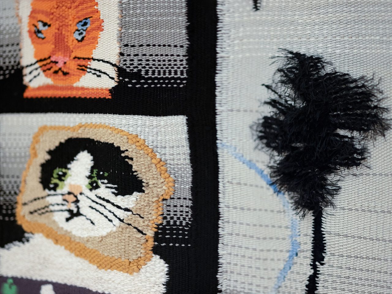 Close up of woven tapestry depicting cats with their face in a slice of bread